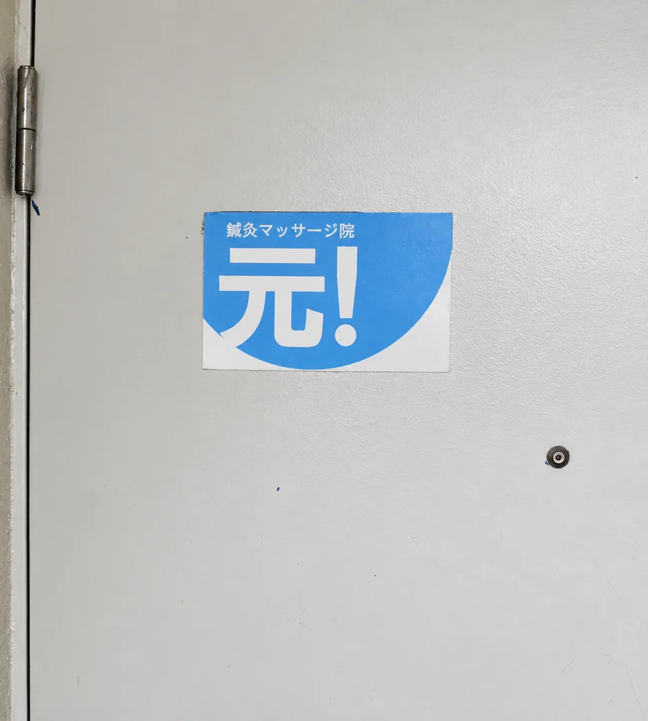 2階の扉にある鍼灸マッサージ院 元！の看板